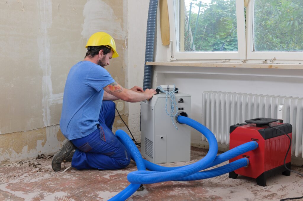Worker adjusting dehumidifier in an apartment which is damaged by flooding