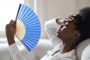 Relief Services: Air Conditioning, Plumbing, Septic, and Water Restoration in Apollo Beach, FL 4 Afro business woman suffering from heat stroke sitting in living room at home using waving fan